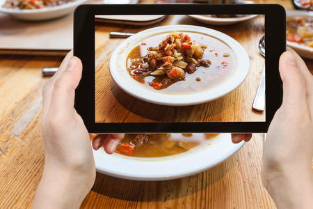 travel concept - tourist photographs the lunch with Kjotsupa, traditional Icelandic Lamb Soup in Reykjavik city restaurant on tabletの写真素材