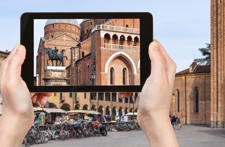 travel concept - tourist photographs monument of Gattamelata by Donatello and Basilica of Saint Anthony of Padua on square piazza del Santo in Padua city in Italy on tabletの写真素材
