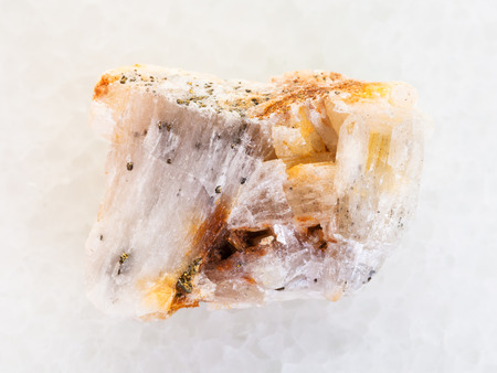 macro shooting of natural mineral rock specimen - native gold in rough quartz stone on white marble backgroundの写真素材