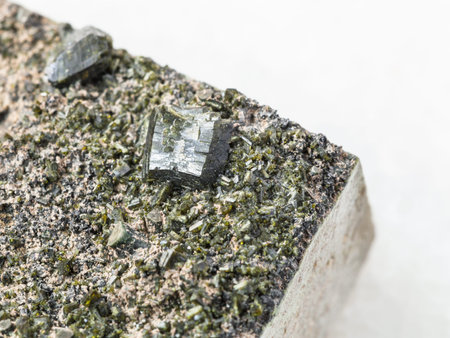 macro shooting of natural mineral stone specimen - crystals of Epidote close up on stone on white...