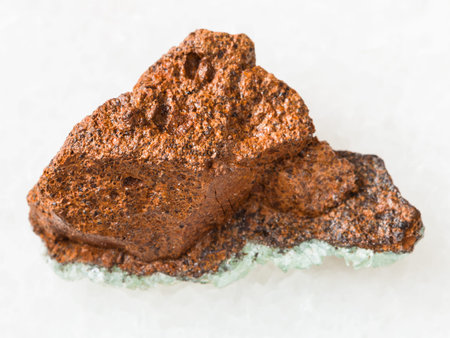 macro shooting of natural mineral rock specimen - raw bog iron ore ( limonite) stone on white marble...