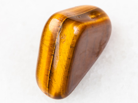 macro shooting of natural mineral rock specimen - tiger-eye gem stone on white marble background from South Africaの写真素材