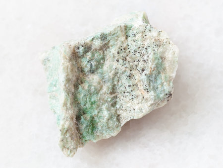 macro shooting of natural mineral rock specimen - raw Listwanite stone on white marble background