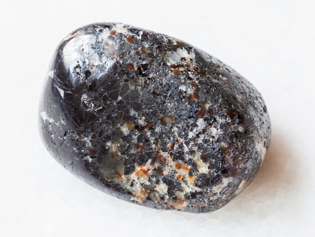 macro shooting of natural mineral rock specimen - tumbled magnetite stone on white marble background from Kovdor district of Kola Peninsula, Russiaの写真素材