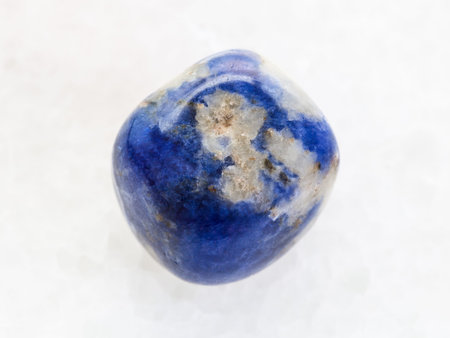 macro shooting of natural mineral rock specimen - polished Sodalite gemstone on white marble...