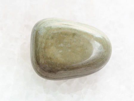 macro shooting of natural mineral rock specimen - tumbled gray Agate gemstone on white marble...