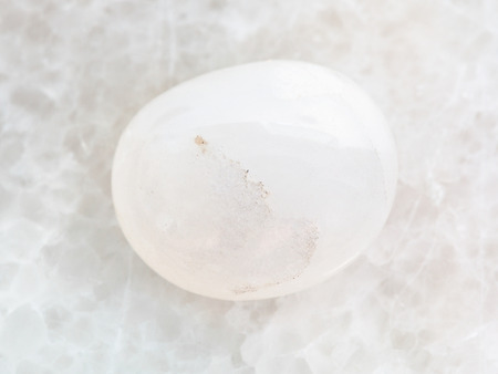 macro shooting of natural mineral rock specimen - polished milky quartz gemstone on white marble backgroundの写真素材
