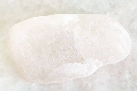 macro shooting of natural mineral rock specimen - pebble of white marble on white marble background...