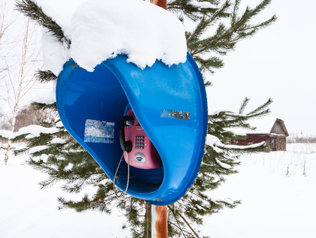 FEDOSOVO, RUSSIA - FEBRUARY 24, 2018: outdoor telephone booth in snow field in village. Working public telephone should be in every populated hamlet of Russia, regardless of the number of inhabitantsのeditorial素材
