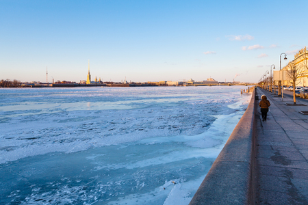 Dvortsovaya Embankment along frozen Neva river and view of Peter and Paul Fortress in Saint Petersburg city in March eveningの写真素材