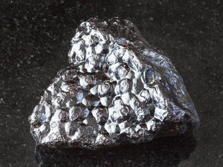 macro shooting of natural rock specimen - raw Hematite (Kidney Ore) stone on black granite...
