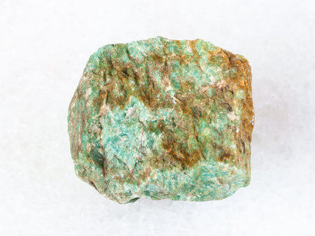 macro shooting of natural mineral - rough Amazonite stone on white marble from Ural Mountains