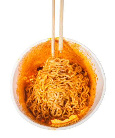 top view of wooden chopsticks in cup with prepared spicy instant noodles isolated on white backgroundの写真素材