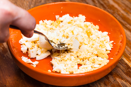 cooking of pie - grinding the boiled eggs for stuffing by forkの写真素材