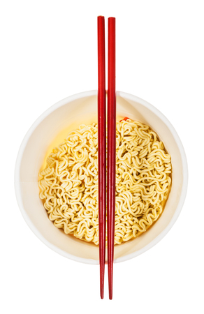 red wooden chopsticks on open cup with dried instant noodles isolated on white backgroundの写真素材