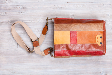 striped brown leather shoulder bag on gray wooden tableの写真素材