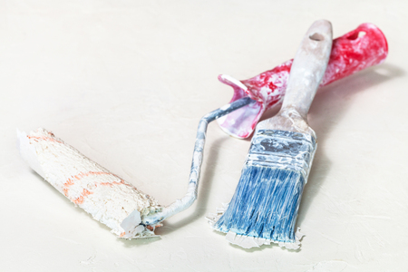 used dried little paint roller and painting brush on white plastered surfaceの写真素材