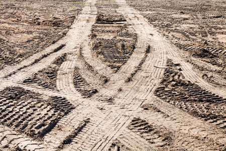 symmetrical traces of car tires on dirty field in sunny autumn dayの写真素材