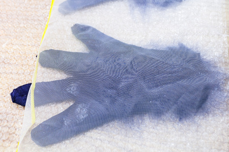workshop of hand making a fleece gloves from blue Merino sheep wool using wet felting process - wet glove with new fibers under plastic meshの写真素材