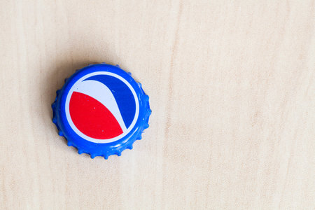 MOSCOW, RUSSIA - APRIL 4, 2019: used crown cork bottle cap from Pepsi beverage on wooden board with...