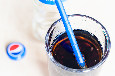 MOSCOW, RUSSIA - APRIL 4, 2019: top view of Pepsi beverage in glass with blue drinking straw close up. Pepsi is carbonated soft drink manufactured by PepsiCoのeditorial素材
