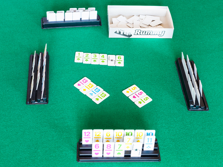 MOSCOW, RUSSIA - APRIL 3, 2019: gameplay of Rummy tile-based card game on green baize table. Rummy is tile and card game based on matching cards of the same rank or sequence and same suitのeditorial素材