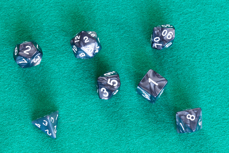 set of gray polyhedral dices for Dungeons and Dragons board game playing on green baize tableの写真素材