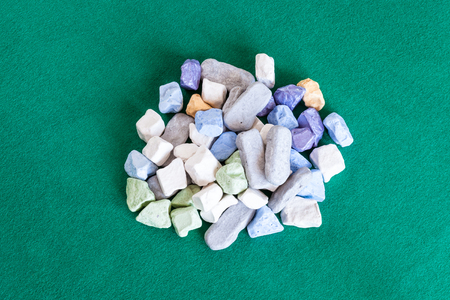 top view of pile of various multicolored stones on green baize tableの写真素材