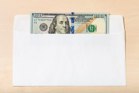 united states one hundred dollars bill in open mail envelope on wooden table