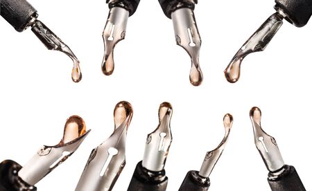 Set of steel nibs with pink ink drops close up on dip pen isolated on whiteの写真素材