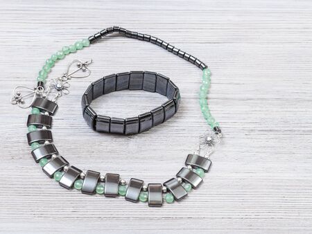 needlecraft background - handcrafted necklace from green jade, black hematite and silver beads and hematite bracelet on gray wooden board with copyspaceの写真素材