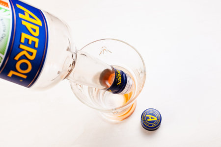 MOSCOW, RUSSIA - MAY 10, 2020: poiring of last drops of drinks from empty bottle of Aperol in glass. Aperol is classic Italian bitter aperitif from Padua city, now it is produced by Campari Groupのeditorial素材