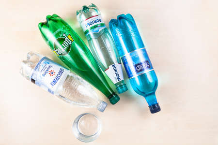 MOSCOW, RUSSIA - MAY 10, 2020: top view of various lying plastic bottles with naturally carbonated mineral waters (Borjomi, Perrier, Selters, Gerolsteiner) and glass on light brown tableのeditorial素材