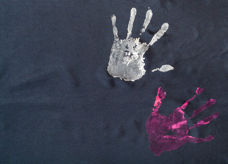 detail of pattern with handpainted handprints on handcrafted black silk scarf isolated on white...