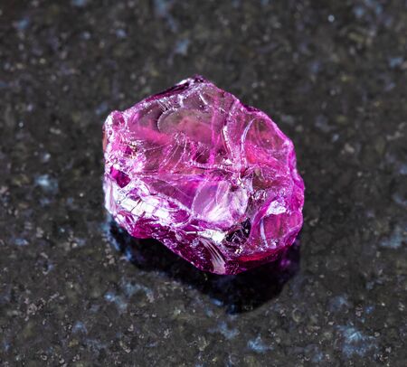 closeup of sample of natural mineral from geological collection - rough Rhodolite (pyrope garnet) crystal on black granite background from Lokirima, Lodwar, Turkana dist, Riffvalley prov, Kenyaの写真素材