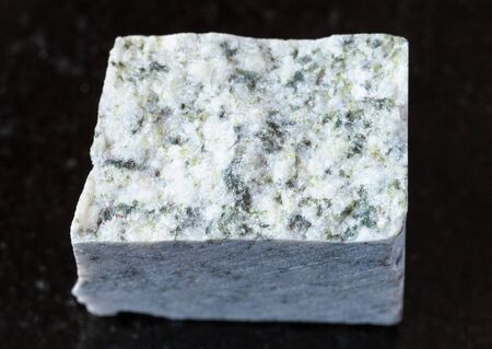 closeup of sample of natural mineral from geological collection - rough white Granite rock on black granite backgroundの写真素材