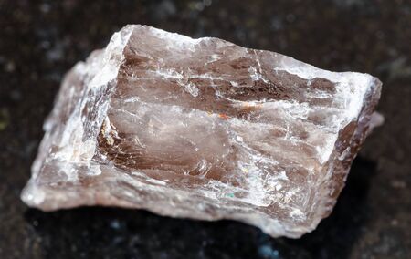 closeup of sample of natural mineral from geological collection - raw Smoky Quartz rock on black granite backgroundの写真素材