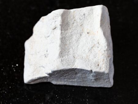 closeup of sample of natural mineral from geological collection - rough Chalk stone on black granite background from Voronezh region, Russiaの写真素材