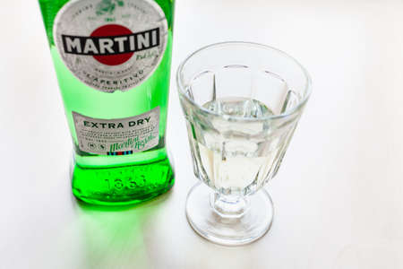 MOSCOW, RUSSIA - MAY 23, 2020: wineglass with drink and bottle of Martini Extra Dry on light brown table. Martini is classic Italian vermouth from Turin city, now this brand belongs to Bacardiのeditorial素材