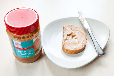MOSCOW, RUSSIA - JUNE 16, 2020: above view of jar of Hy-Top creamy Peanut butter and toast with spread on plate on table. HyTop is brand of private label groceries created in the 1950 in Illinois, USAのeditorial素材