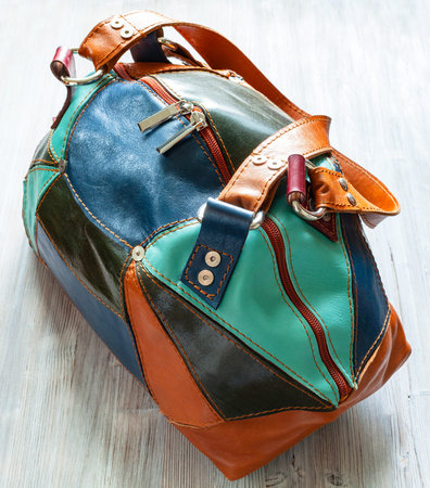 handmade patchwork leather travel bag on gray wooden board