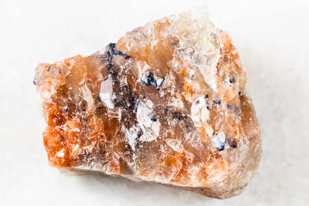 closeup of sample of natural mineral from geological collection - rough red Rock Salt (Halite) on white marble background from Perm Krai, Russiaの写真素材