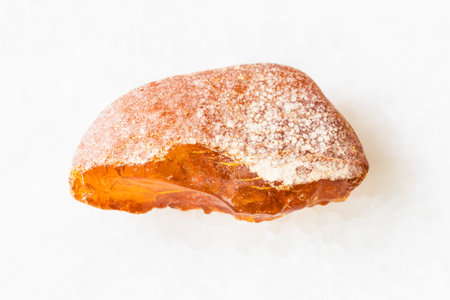 closeup of sample of natural mineral from geological collection - rough Amber gemstone on white...