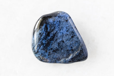 closeup of sample of natural mineral from geological collection - tumbled Dumortierite rock on white...