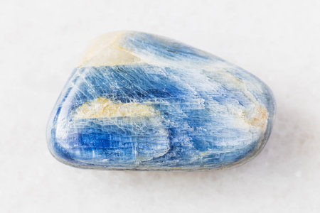 closeup of sample of natural mineral from geological collection - tumbled Kyanite rock on white...