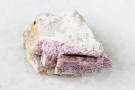 macro photography of sample of natural mineral from geological collection - raw pink Tourmaline mineral in feldspar and quartz rock from Kalba Range, Kazakhstan on white marble backgroundの写真素材