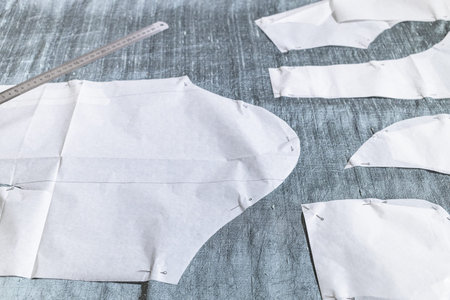 fixed paper sewing pattern layouts of dress and steel ruler on gray fabric