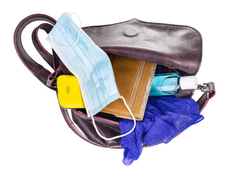 top view of woman's bag with protective mask, sanitizer, gloves, wallet and smartphone isolated on...