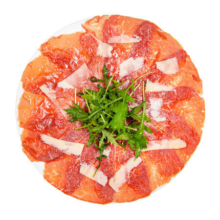 top view of served Carpaccio (thinly sliced raw beef fillet) decorated by Parmesan, Arugula on white plate isolated on white backgroundの写真素材