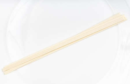 several dried flat Udon noodles from wheat flour on white plateの写真素材